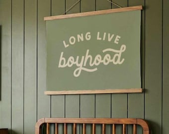 May include: A room with a green wall, a wooden bed, and a framed landscape painting. A green poster with the words "LONG LIVE boyhood" hangs above the bed. Two pillows with a longhorn design rest on the bed.