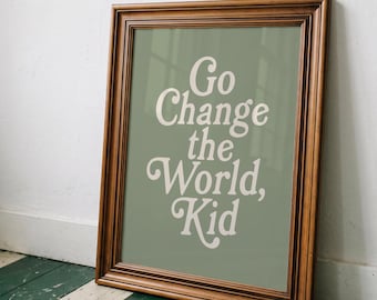 May include: A rectangular wall art print in a dark brown wooden frame. The print features a sage green background with the off-white text Go Change the World, Kid written in a bold, rounded, serif typeface centered on the surface of the print.