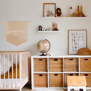 a dusty pink coloured banner in a neutral style nursery. You can personalise this with any name