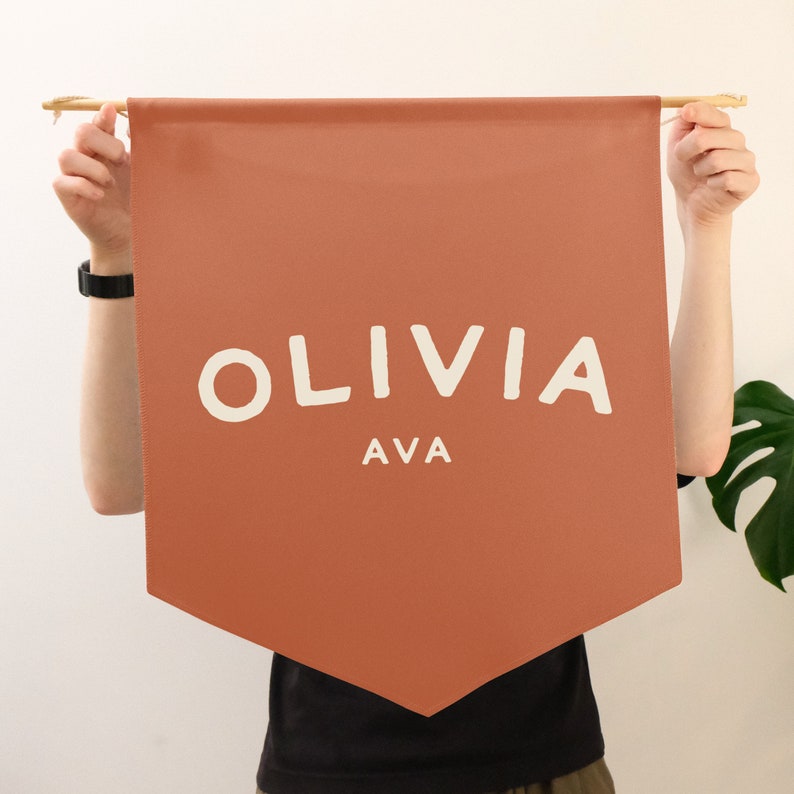 a orange coloured pennant banner that you can customise with any name, being held up
