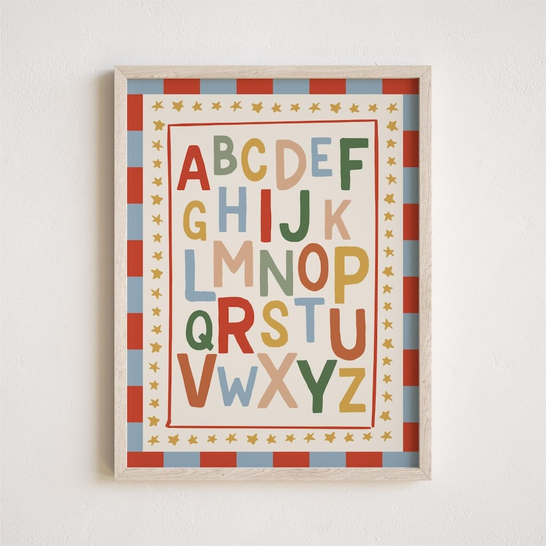 May include: A framed alphabet print with a cream background. The letters A through Z are in various colors. The frame has a red and blue striped border, with gold stars around the inner edge. The print is designed for children's rooms.