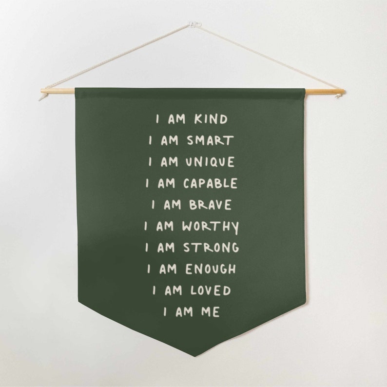 May include: A dark green fabric banner with white text that reads "I am kind, I am smart, I am unique, I am capable, I am brave, I am worthy, I am strong, I am enough, I am loved, I am me".