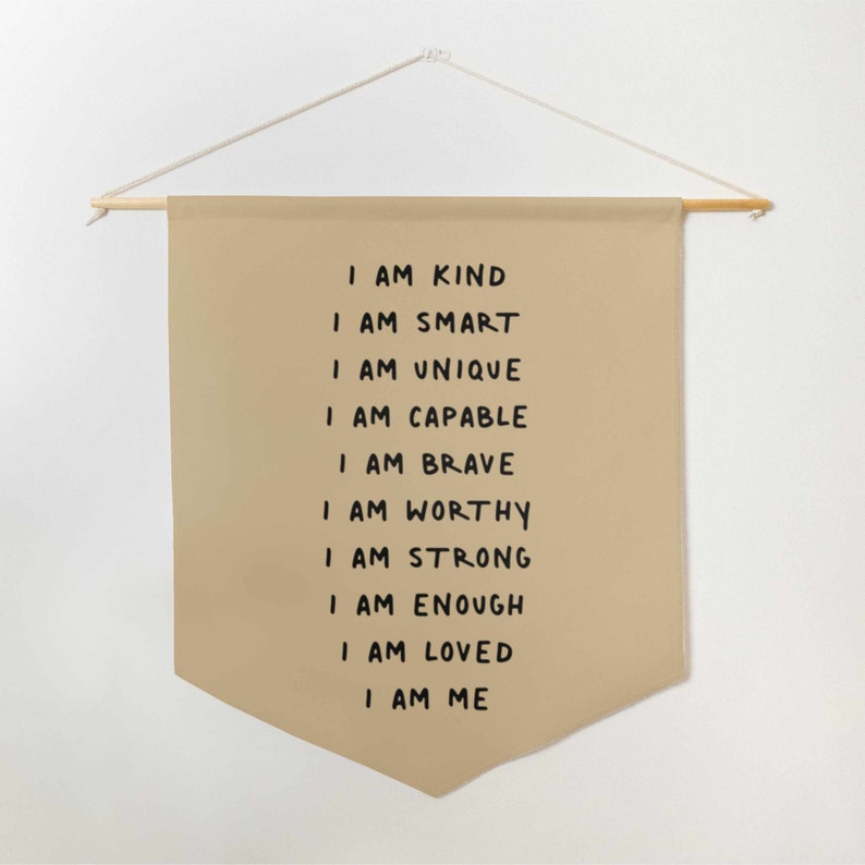 May include: A beige canvas wall hanging with the text "I am kind, I am smart, I am unique, I am capable, I am brave, I am worthy, I am strong, I am enough, I am loved, I am me" written in black.