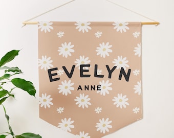 May include: A peach-colored fabric banner with a white daisy pattern. The banner has the name "EVELYN ANNE" printed in black.