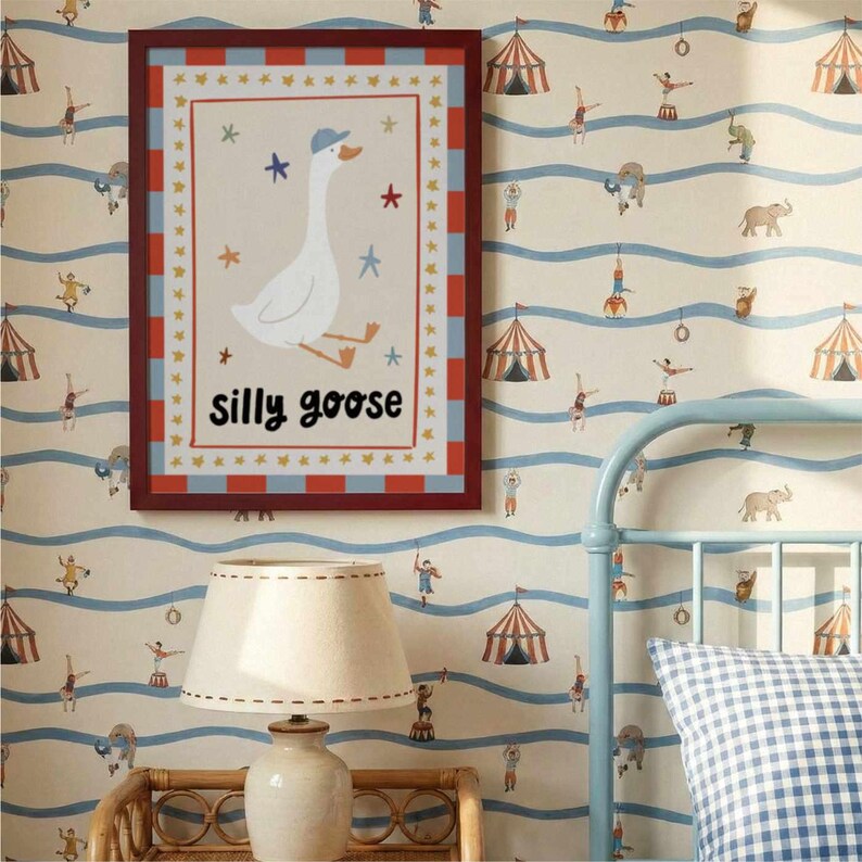 May include: A framed print featuring a whimsical illustration of a goose wearing a blue cap, with the words "silly goose" below. The frame has a red border with blue and white accents. The background is a circus-themed wallpaper.
