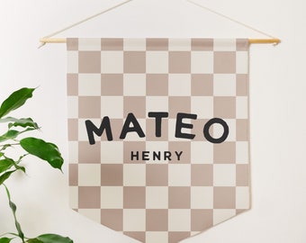 May include: A rectangular fabric wall banner featuring a beige and white checkered pattern. The text MATEO is printed in large, bold, black sans-serif letters, with the name HENRY printed below in smaller, black, capitalized sans-serif letters.