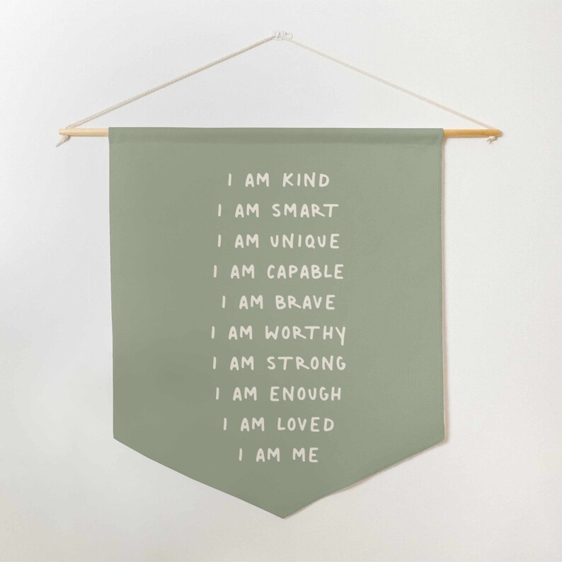 May include: A green fabric banner with white text that reads "I am kind, I am smart, I am unique, I am capable, I am brave, I am worthy, I am strong, I am enough, I am loved, I am me".