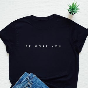 May include: Black t-shirt with the text "BE MORE YOU" in white lettering.