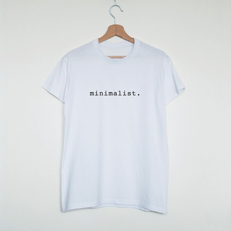 May include: White t-shirt with the text "minimalist." printed in black on the front.