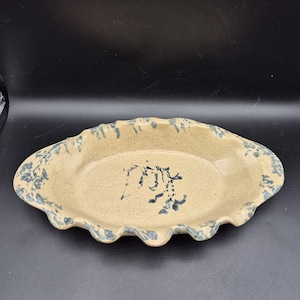 Peut inclure: Plat de service ovale en céramique avec une base beige et une bordure florale bleue. Le plat a un bord festonné et un motif floral bleu au centre. Une pièce décorative pour servir des aliments ou exposer des objets.