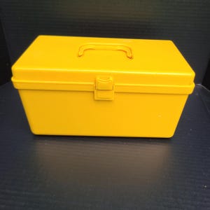 May include: A bright yellow plastic storage box with a carrying handle and a latch. The box is empty.