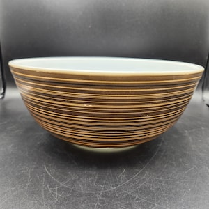 May include: A brown and white striped mixing bowl with a white interior. The bowl has a vintage look and is made of glass.