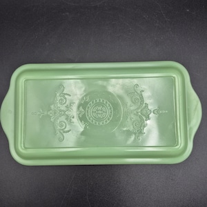 Peut inclure: Un plateau de service rectangulaire vert clair avec des coins arrondis et des poignées. Le plateau présente un motif floral et de volutes en relief au centre. Le plateau est fait d'un matériau solide et durable.
