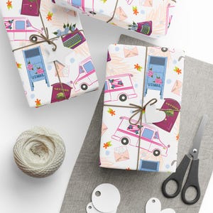 May include: Gift-wrapped packages with a white background featuring a repeating pattern of a postal truck, mailbox, and envelopes. The packages are tied with twine and adorned with decorative tags. A ball of twine, scissors, and tags are also visible.