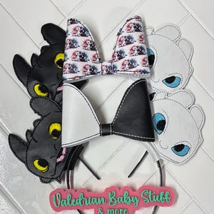 May include: A collection of headbands featuring character designs. The headbands include black and white bows, and character cutouts. One bow has a print of characters. The text "Valedrian Baby Stuff & more" is visible on a pink background.