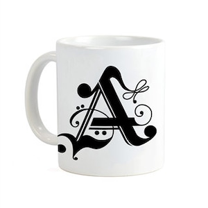 May include: White ceramic mug with a black stylized letter A with decorative flourishes.