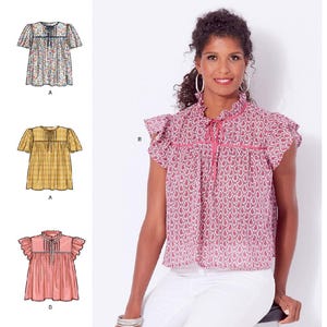 May include: Simplicity sewing pattern S9546. The image shows a woman wearing a pink paisley top with a ruffled collar and sleeves. The pattern includes illustrations of similar tops in different colors and patterns. The text "easy-to-sew" is visible.