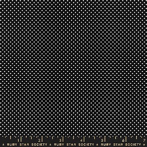 May include: Black fabric with a white polka dot pattern. The fabric is shown with a ruler for scale.