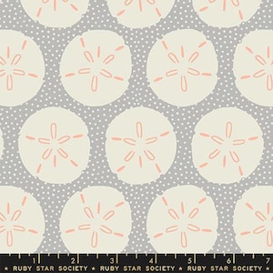May include: A seamless fabric pattern featuring a repeating design of sand dollars on a gray background with white polka dots. The sand dollars are a light beige color with a coral pink center.