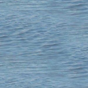 May include: A close-up shot of the ocean's surface, showcasing gentle waves in varying shades of blue. The water's texture is visible, with subtle ripples and reflections creating a serene and natural scene. The image captures the essence of the sea.