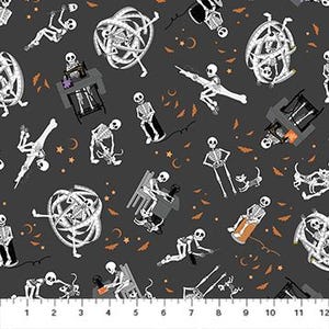 May include: Dark gray fabric with a repeating pattern of white skeletons in various poses, including sewing, dancing, and lounging. Orange bats, crescent moons, and stars are scattered throughout the design. The fabric has a ruler along the bottom edge with measurements in inches.