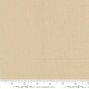 May include: Tan fabric with a vertical ribbed texture. The fabric has a subtle sheen and a ruler is at the bottom. The fabric is from Moda Fabrics.