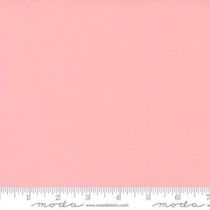 May include: A solid pink fabric swatch with a ruler showing 7 inches. The ruler has the word "moda" printed on it.