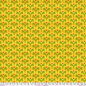 May include: A yellow fabric featuring a repeating pattern of stylized green leaf-like shapes and small red dots. A white ruler with black markings is visible along the bottom edge, showing measurements in inches from 0 to 24 inches.