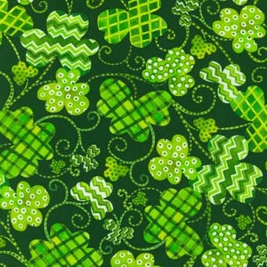 May include: A green fabric with a repeating pattern of shamrocks in various styles. The shamrocks are green with white accents and are arranged in a random pattern.