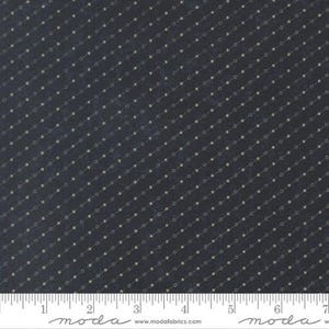 May include: Dark navy fabric with a repeating pattern of small, light tan dots arranged in diagonal lines. A ruler with inch markings is at the bottom. The fabric is from Moda Fabrics.