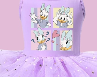 Puede incluir: Un vestido sin mangas de color morado claro con tirantes finos y una falda de tul de varias capas con estrellas doradas. El corpiño muestra un estampado gráfico de cuatro paneles de un pato blanco con un lazo azul. Un logo circular dice Copper Arrowz Tutu Boutique.