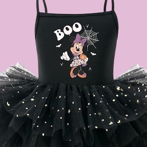 May include: A black sleeveless leotard dress with thin straps featuring a graphic of Minnie Mouse holding a pumpkin, the text BOO, and a spiderweb. The skirt consists of multiple layers of black tulle embellished with small gold star accents.