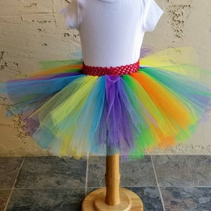 Puede incluir: Una falda de tut&uacute; de tul arco&iacute;ris con una cintura de crochet roja. La falda est&aacute; en un maniqu&iacute; blanco.