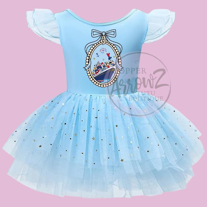 May include: A light blue tutu dress with a boat graphic. The bodice has a boat graphic with cartoon characters and a bow. The skirt is layered with tulle and gold star accents. The sleeves are short and ruffled.