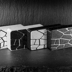 Peut inclure: Quatre petites boîtes rectangulaires avec un motif géométrique. Les boîtes sont noires et blanches et ont une surface texturée.
