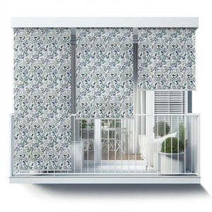 May include: White balcony with three white window shades featuring a blue and green leafy pattern. The shades are pulled down to cover the windows. The balcony has a white railing and a white floor. There is a white table and chairs on the balcony, as well as a white couch and a potted plant.