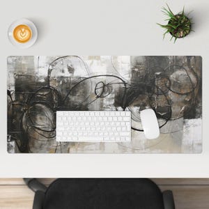 Könnte beinhalten: Abstrakte Kunst Schreibtischmatte mit schwarzen und grauen Wirbeln auf weißem Hintergrund. Eine weiße Tastatur und Maus befinden sich auf der Matte.