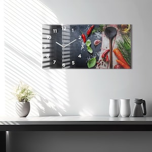 Könnte beinhalten: Eine Küchenuhr mit schwarzem Hintergrund und weißen Zahlen. Das Zifferblatt der Uhr ist von verschiedenen Kochzutaten umgeben, darunter rote Chilischoten, Knoblauch, Kräuter und ein Holzlöffel.