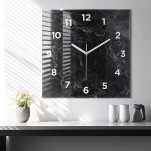 May include: A black and white marble clock with white numbers and hands. The clock is square and has a glass face.