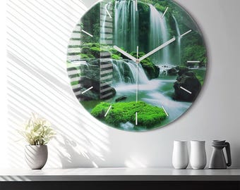 May include: A circular wall clock featuring a high-resolution photographic print of a lush green forest waterfall cascading over mossy rocks. The clock face has thin, silver-colored hour and minute hands and simple white tick marks for the hours.