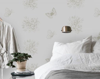 May include: A white bedroom with a bed with a gray blanket and white pillows. The wall has a light gray floral wallpaper with a pattern of butterflies and bouquets of flowers.