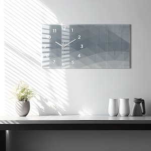 May include: A modern gray and white clock with a geometric design. The clock has a white face with black numbers and hands.
