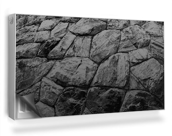 May include: Black and white photograph of a stone wall. The wall is made of large, irregularly shaped stones that are tightly fitted together. The stones are all different sizes and shapes, and they create a textured and interesting surface.