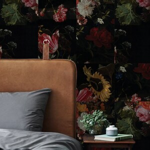 Peut inclure: Une tête de lit en cuir marron avec une housse de couette grise et une table de chevet avec une plante verte et une bouteille décorative. Le mur derrière le lit est recouvert d'un papier peint floral à fond noir et aux fleurs colorées.