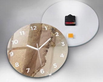 May include: A round wall clock featuring an abstract design with shades of brown, beige, and gold metallic accents. The clock face displays white numerals from 1 to 12 and white hour and minute hands. The back shows a black battery mechanism.