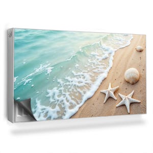 Op de afbeelding: Een strandscene met een golf die aan de kust breekt. Het zand is lichtbruin en er zijn drie witte zeesterren en twee witte schelpen.
