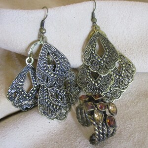 May include: A pair of gold-tone dangle earrings with a filigree design and a smaller ring with brown stones.