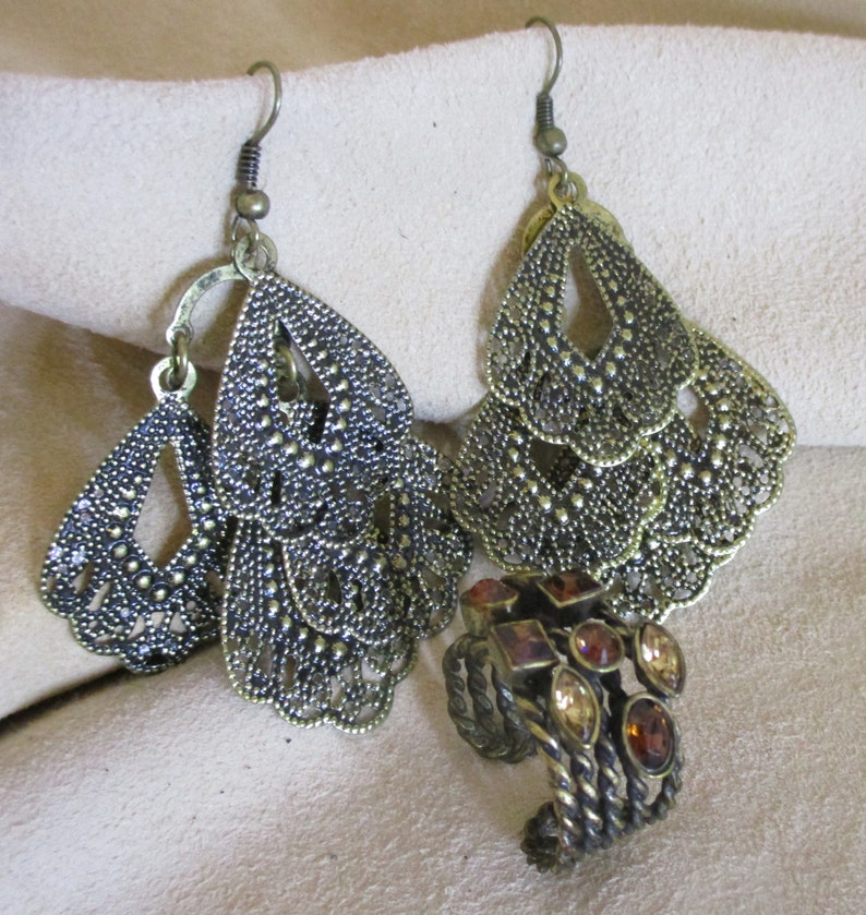 May include: A pair of gold-tone dangle earrings with a filigree design and a smaller ring with brown stones.