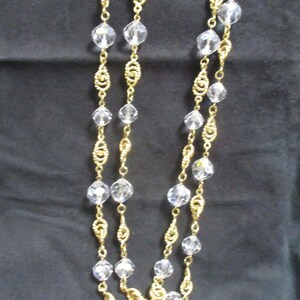 May include: A gold chain necklace with clear crystal beads. The chain is made of twisted gold wire.