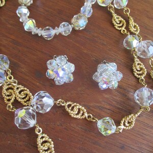 May include: A set of vintage crystal jewelry featuring a long necklace with gold chain and large faceted crystal beads, a shorter necklace with faceted crystal beads, and a pair of crystal earrings.